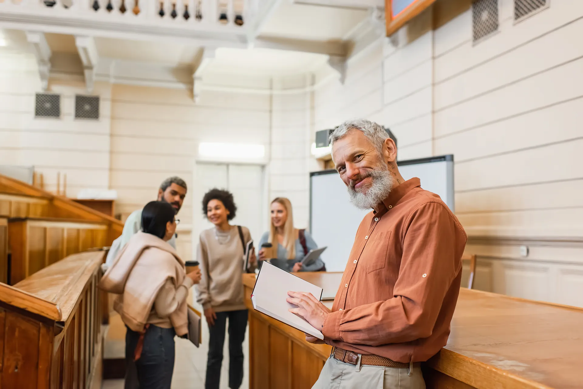 Professor smiling at the front of a hybrid lecture room
